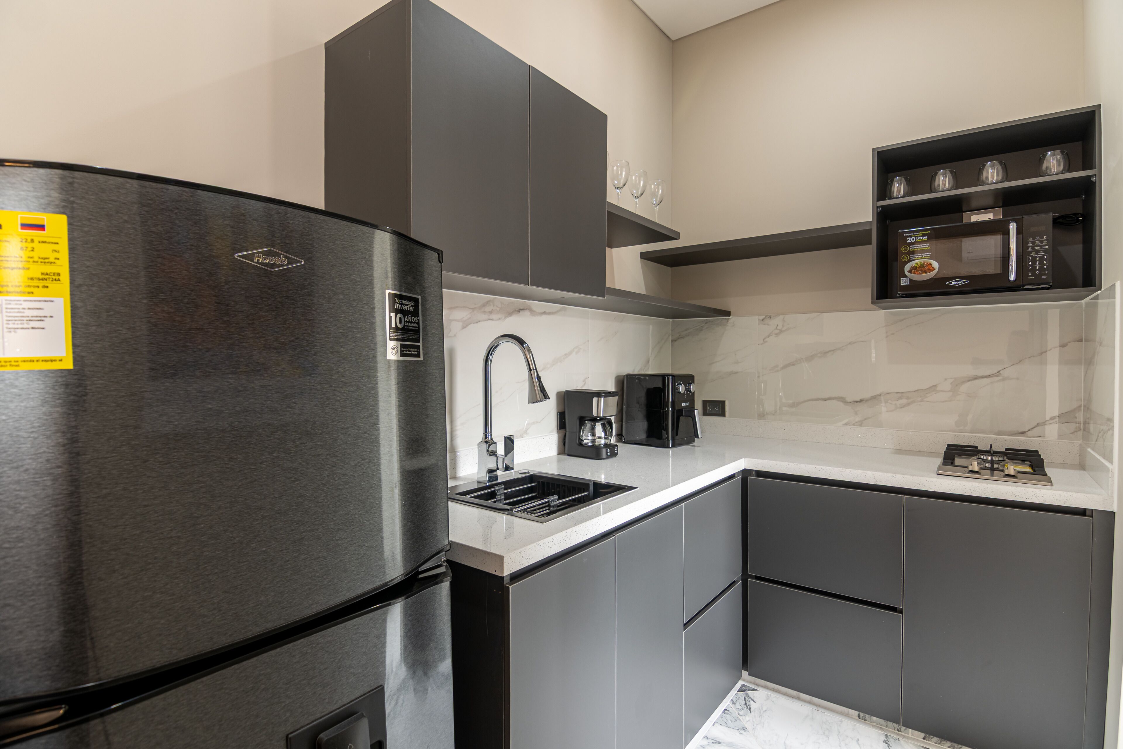 A modern kitchen with a stainless steel refrigerator, a coffee maker, and a microwave.