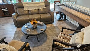 Una sala de estar con un sofá, sillones, una mesa de centro y un piano.