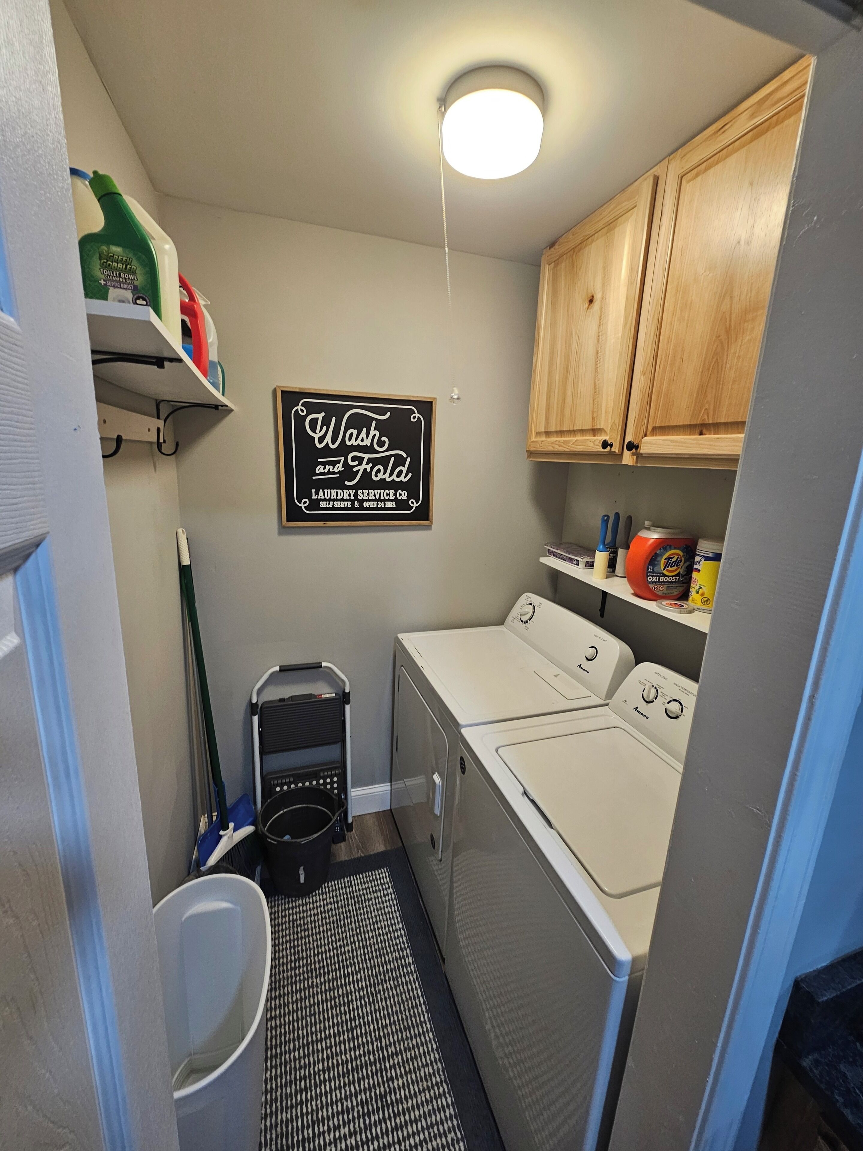 A laundry room with a sign that reads 'Wash and Fold Laundry Service Co. Self Serve & Open 24 Hours.'