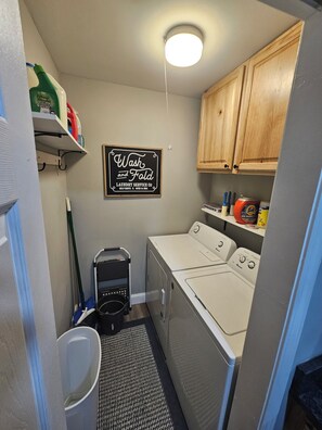 A laundry room with a sign that reads 'Wash and Fold Laundry Service Co. Self Serve & Open 24 Hours.'