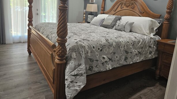 Un dormitorio con una cama con dosel, cabecera de madera y colcha con estampado floral.