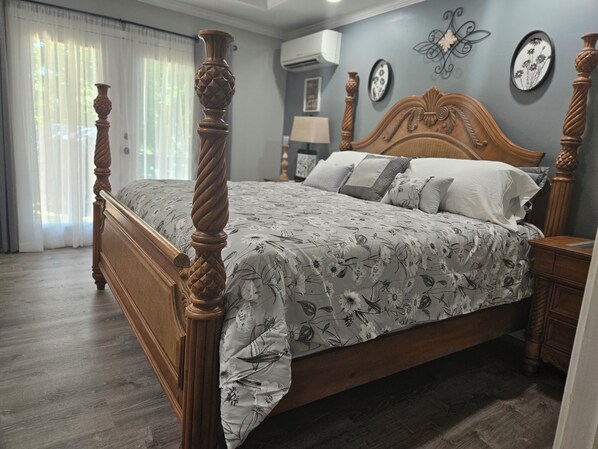 A bedroom with a four-poster bed, a wooden headboard, and a floral-patterned bedspread.