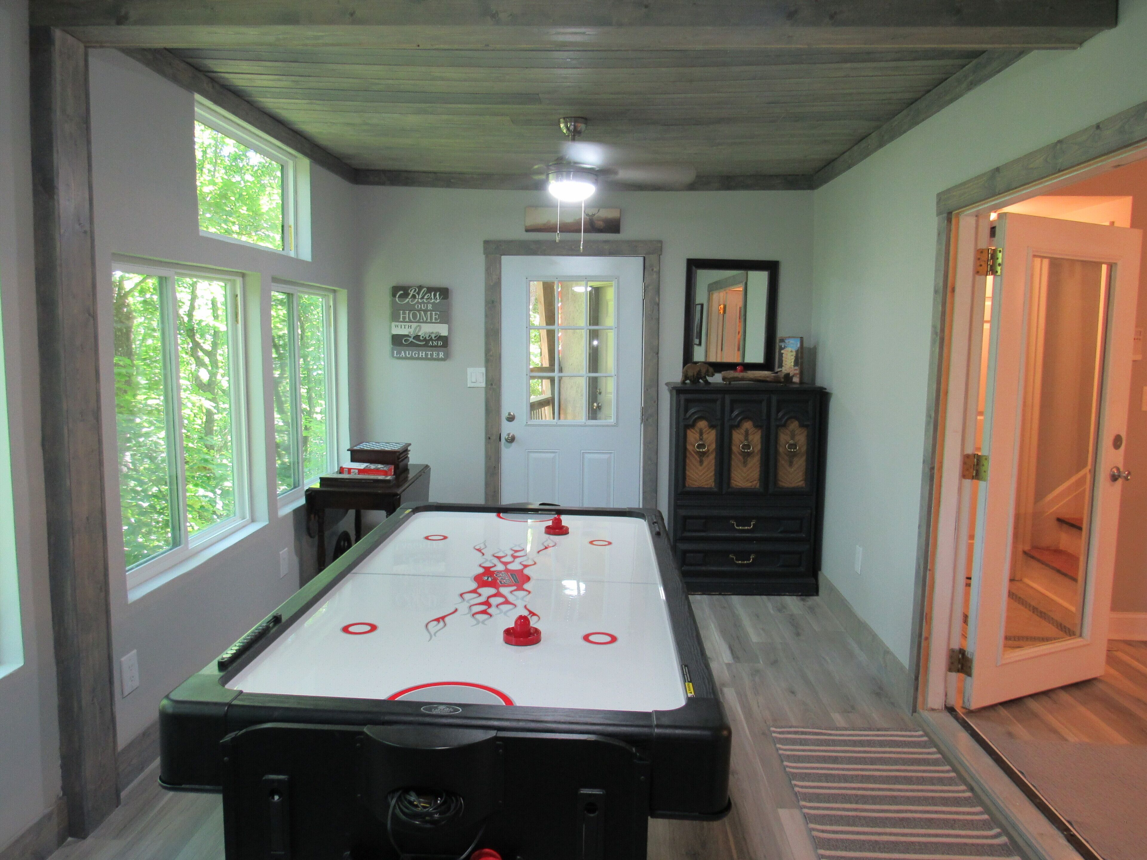 A room with a pool table, a door, and a window.