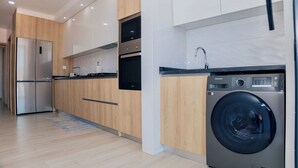 Une cuisine moderne dotée d’appareils électroménagers en acier inoxydable, de meubles de rangement en bois et d’un lave-linge encastré.