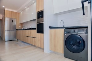 A modern kitchen with stainless steel appliances, wooden cabinets, and a built-in washing machine.