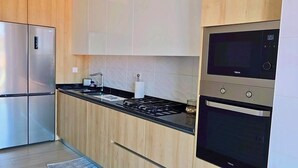 Une cuisine moderne dotée d’appareils électroménagers en acier inoxydable, de meubles en bois et d’un plan de travail noir.
