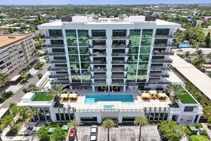 Et hotel med flere etager, en pool på taget og udendørs siddepladser.