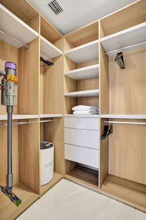 A walk-in closet with multiple storage compartments, a laundry basket, and a vacuum cleaner. - Oceanview Escape 3BR Near Pompano Beach (Pompano Beach)