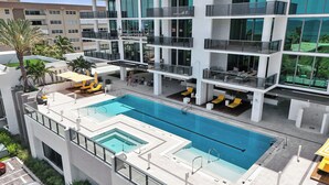 Um edifício moderno com piscina no terraço, várias varandas e áreas de estar ao ar livre.
