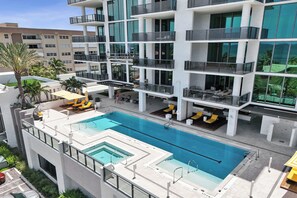 Ein modernes Gebäude mit Pool auf dem Dach, mehreren Balkonen und Sitzbereichen im Freien.