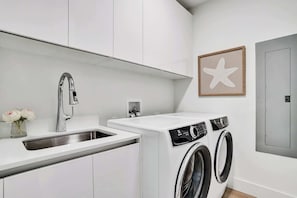 A modern kitchen with a stainless steel sink, a built-in washing machine, and a framed star decoration on the wall. - Oceanview Escape 3BR Near Pompano Beach (Pompano Beach)