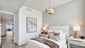 Um quarto moderno com uma cama grande, abajures, uma luminária no teto e vista para o exterior.