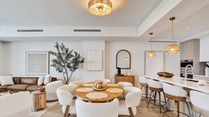 Uma cozinha moderna com ilha central, banquetas e iluminação pendente.