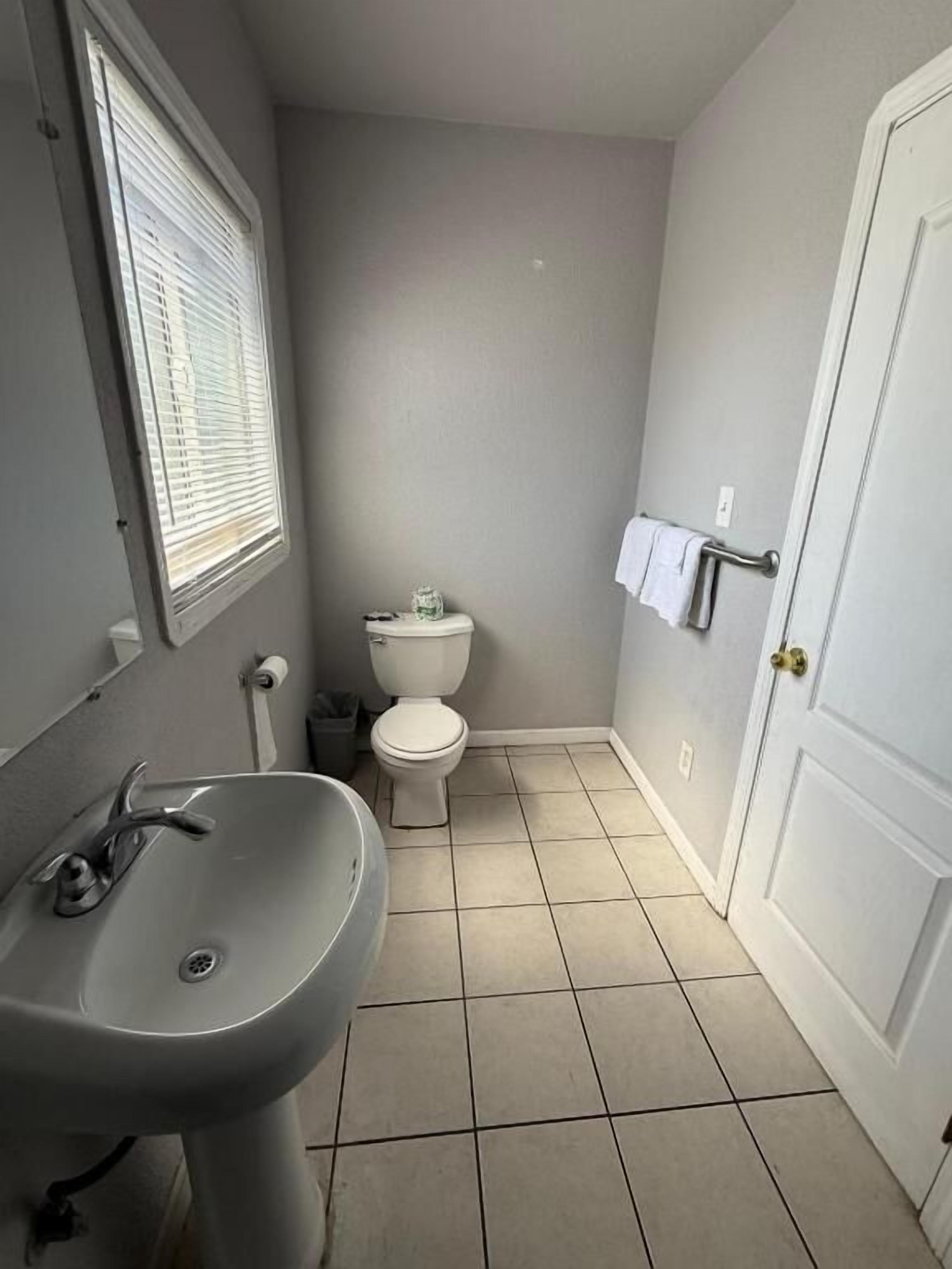 A bathroom with a sink, toilet, and window.