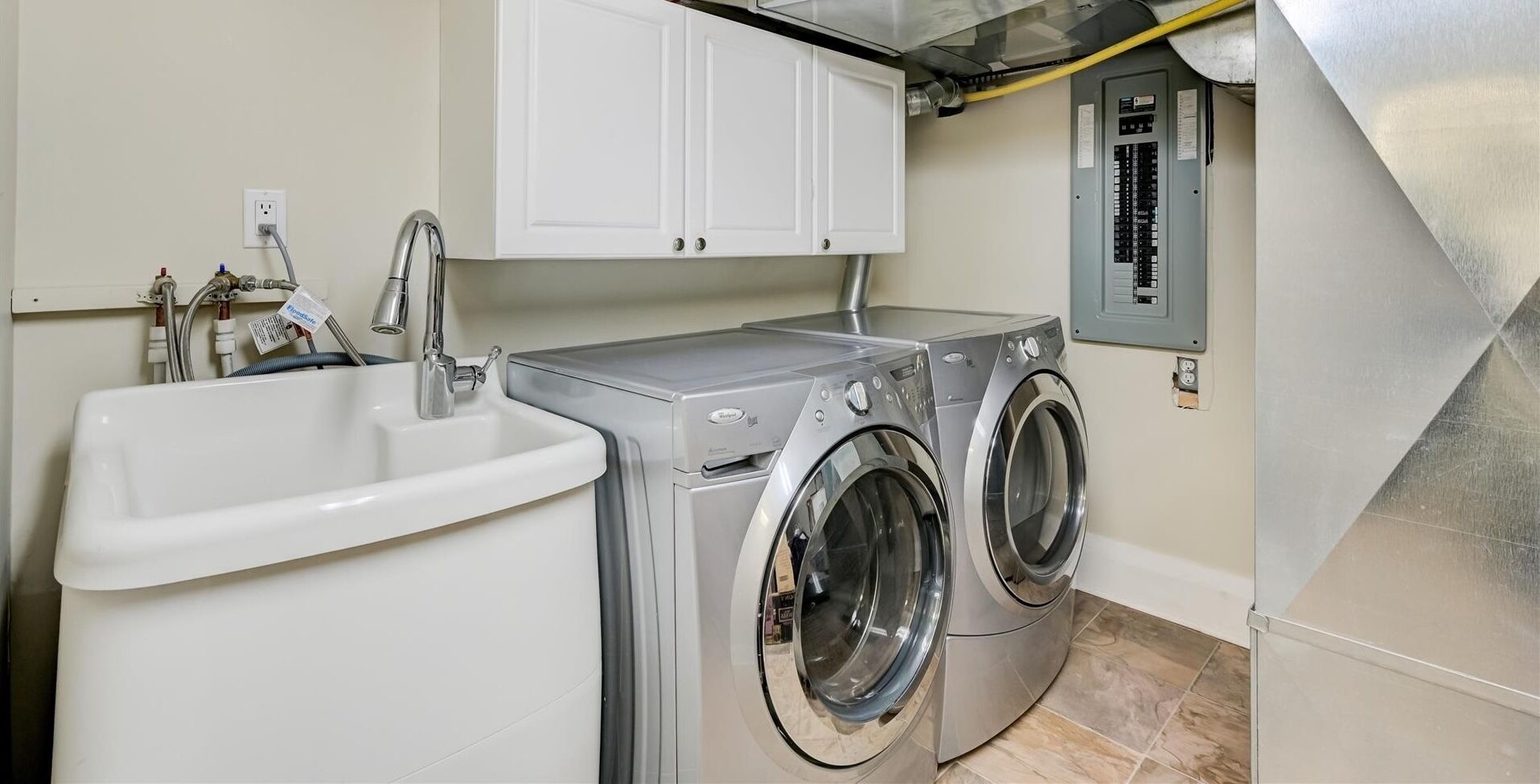 A laundry area with a sink, two washing machines, and a utility panel.