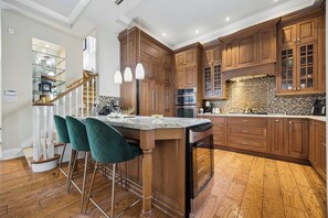 A modern kitchen with wooden cabinets, a marble island, and bar stools. - Elegant 2BR+Office Leaside Home|Free Parking.Ravine.NearLRT. Sunnybrook Hospital (Toronto)