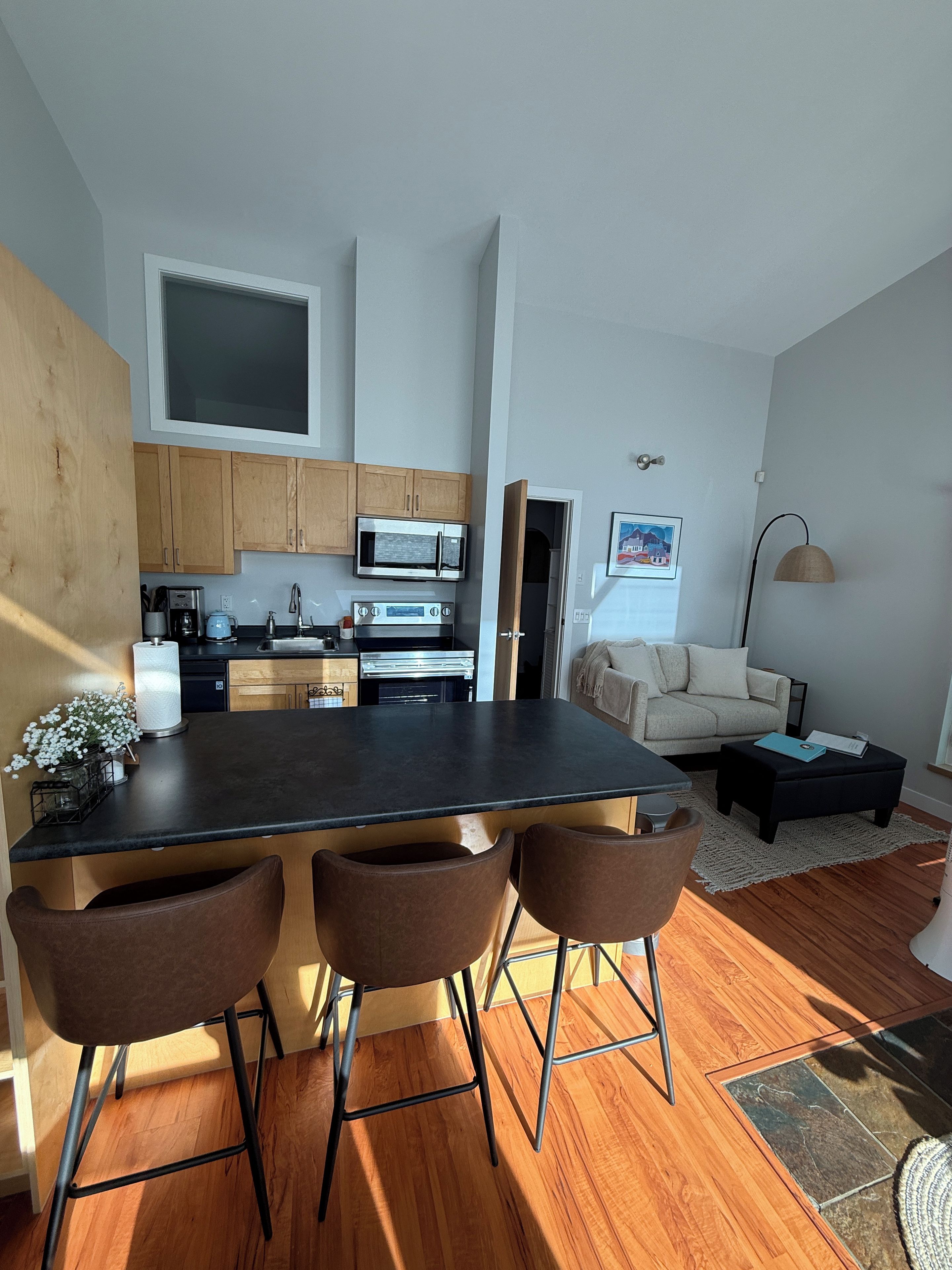 A modern kitchen with a central island, wooden cabinets, and stainless steel appliances.