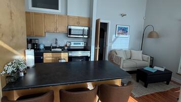 A modern kitchen with a central island, wooden cabinets, and stainless steel appliances.