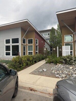A residential area with modern houses, a paved driveway, and a car parked on the street.