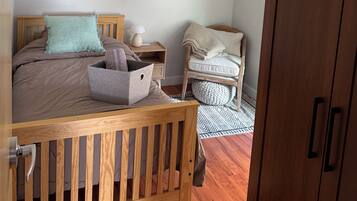 Una camera da letto con un letto in legno, un comodino, una sedia, un armadio e un quadro appeso al muro.