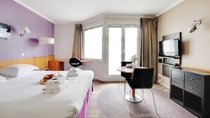A hotel room with a bed, a desk, a chair, a television, and a window with curtains. - Modern Studio - 2P - Issy-les-moulineaux / Javel (La Courneuve)