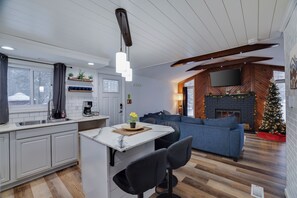 A modern kitchen with a marble countertop, a built-in coffee machine, and a dining area with a blue sofa and a fireplace. - Cozy 3BR w/Jacuzzi, Fireplace, Games near Kalahari (Pocono Summit)