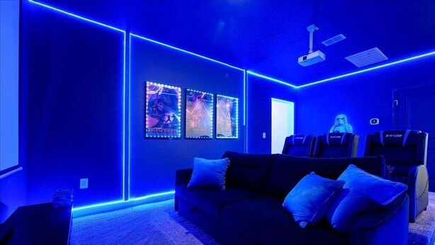 A room with a dark blue color scheme, a sofa, and a projector. - Elegant Villa in ChampionsGate | Near Disney (Davenport)