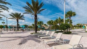 A poolside area with lounge chairs, palm trees, and a clear sky. - Elegant Villa in ChampionsGate | Near Disney (Davenport)