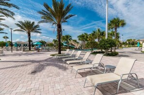 A poolside area with lounge chairs, palm trees, and a clear sky. - Elegant Villa in ChampionsGate | Near Disney (Davenport)