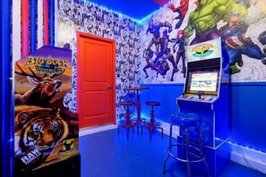 A room with arcade games, a red door, and a wall with superhero posters. - Elegant Villa in ChampionsGate | Near Disney (Davenport)
