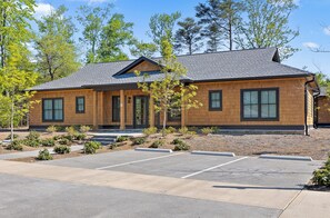 A two-story building with a wooden facade, large windows, and a parking lot in front.