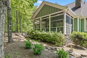 A house with a large glass conservatory, surrounded by trees and a stone wall. - McLemore Resort - 84 Rushing Water Trail - Forest and Pond View (Rising Fawn)