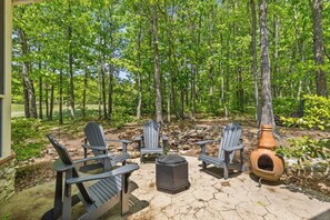 Een terras met Adirondack stoelen, een vuurplaats en een stenen open haard.