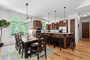 Een moderne keuken met houten kastjes, roestvrijstalen apparatuur en een centraal eiland met barstoelen.