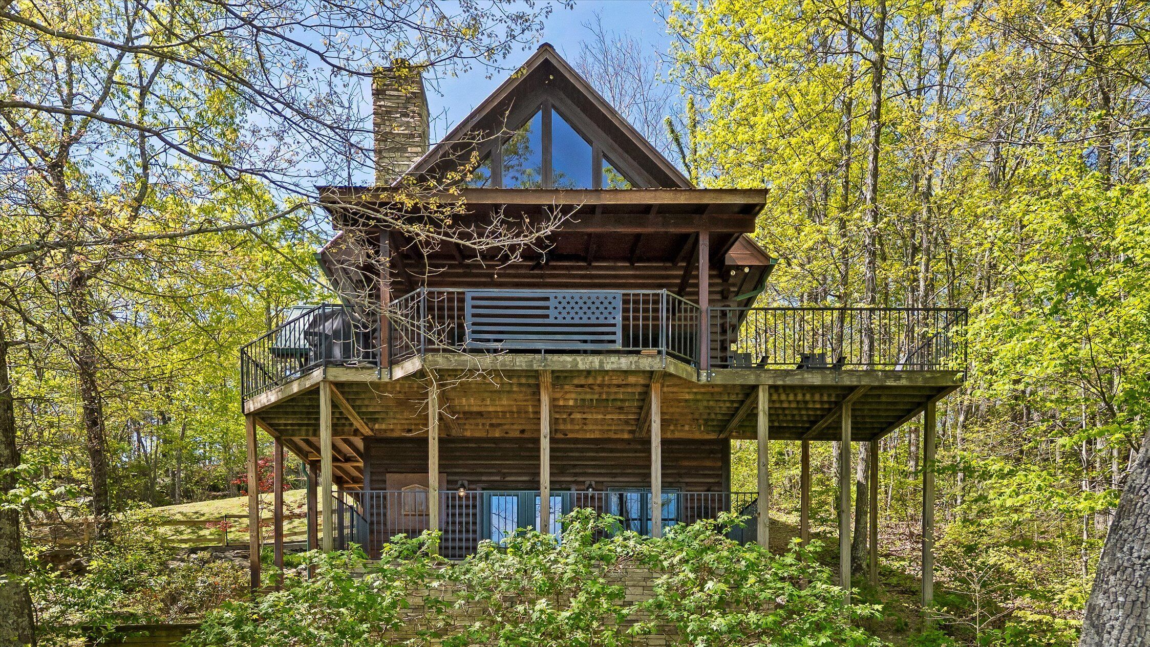 Eine Holz-Hütte mit einem Balkon, umgeben von Bäumen.