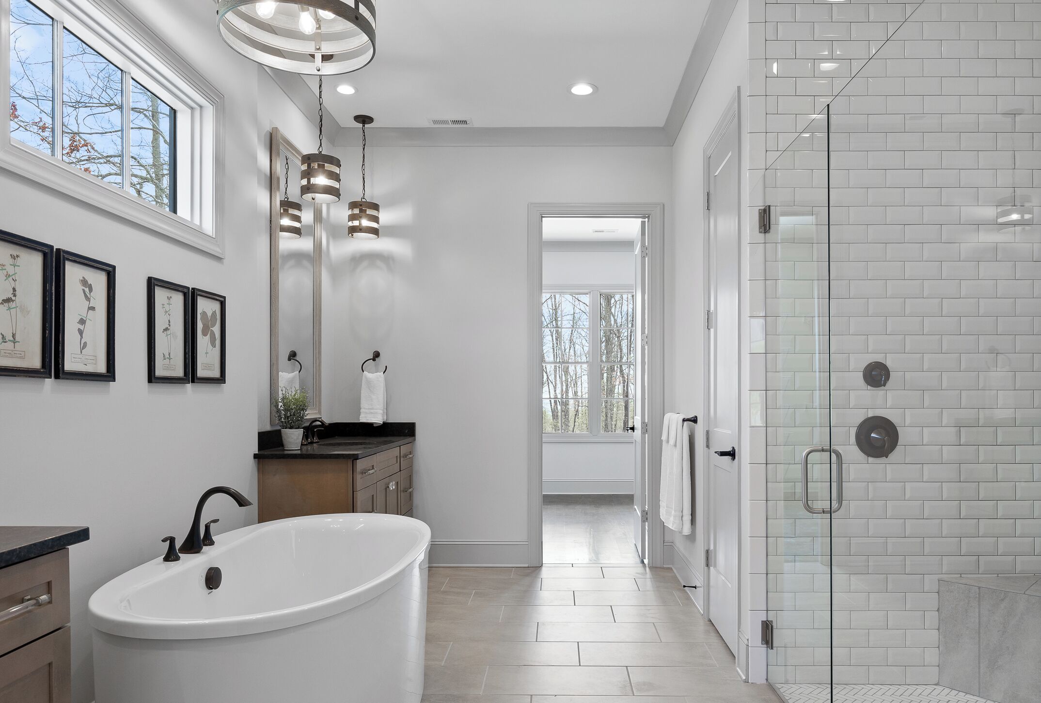 Ein modernes Badezimmer mit einer freistehenden Badewanne, einer Duschkabine aus Glas und einem großen Fenster für natürliches Licht.