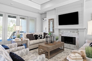 A living room with a fireplace, a television mounted above it, and a sofa with patterned cushions. - McLemore Resort - 156 Rushing Water Trail - Luxury Mountain Home (Rising Fawn)