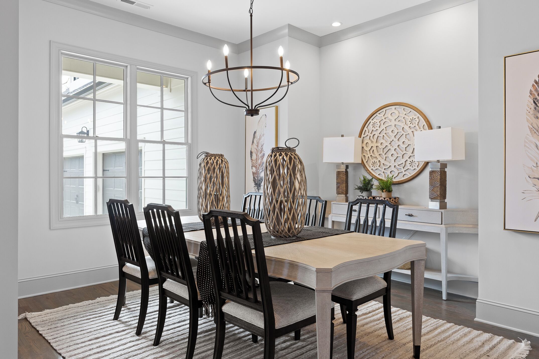 A dining room with a large table, chairs, a chandelier, and decorative wall art.