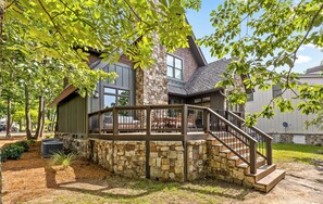 A modern house with a stone foundation, a wooden deck, and a staircase leading to a covered patio area. - McLemore Resort - 56 Founders Path - Walking distance to Range and Clubhouse (Rising Fawn)