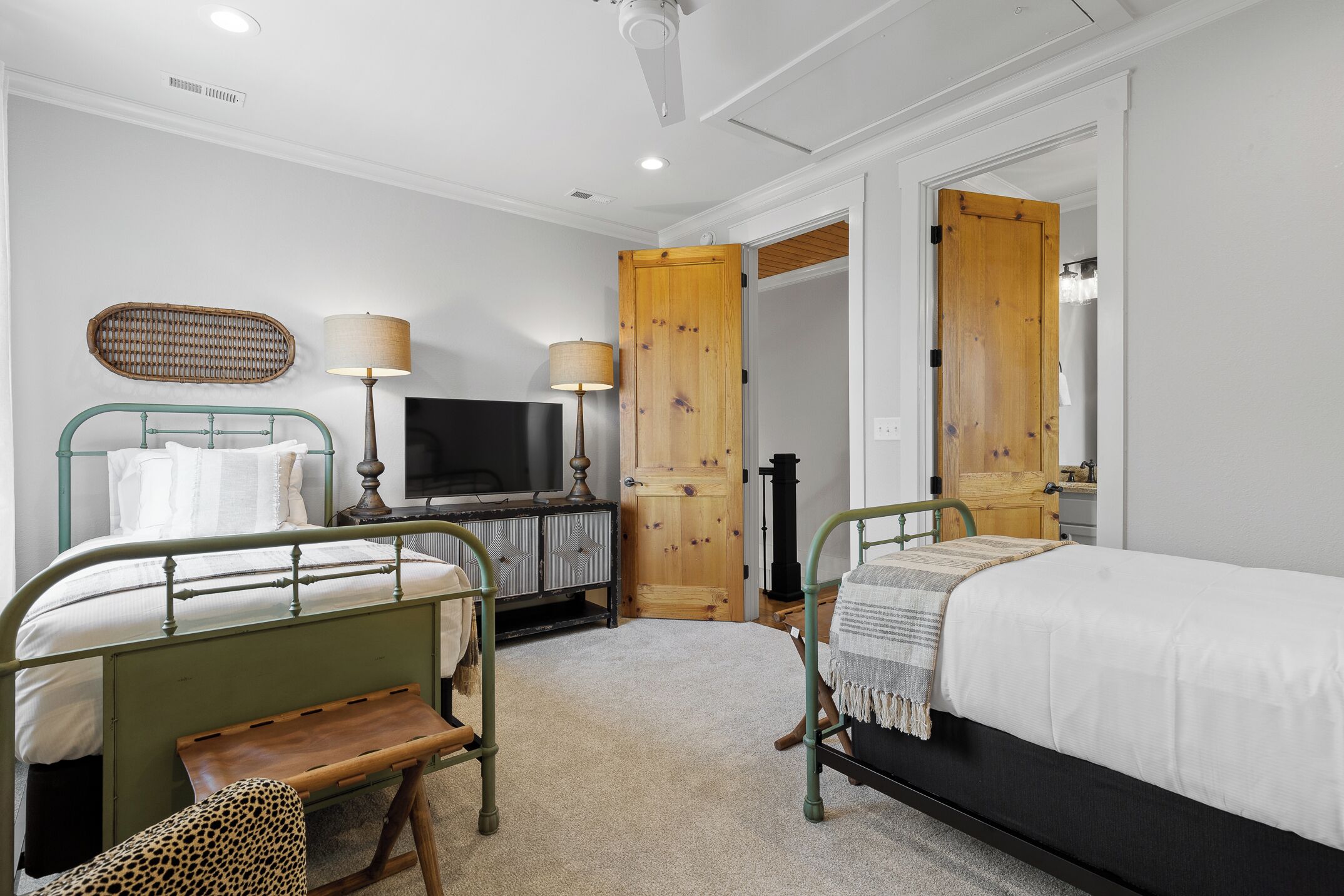 A hotel room with two beds, a television, a wooden door, and a small table.