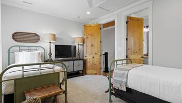 A hotel room with two beds, a television, a wooden door, and a small table.