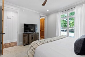 Une chambre à coucher comprenant un lit, une télévision, une armoire et une porte donnant sur un espace extérieur.