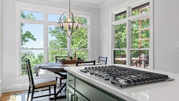 A kitchen with a central island, large windows, and a hanging light fixture.