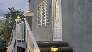 A building with a staircase leading to a door, a window with bars, and a light fixture on the steps. - Peaceful Studio Retreat Near Shoal Bay Beach - AC, Wi-Fi, Concierge Support (Shoal Bay Corner)