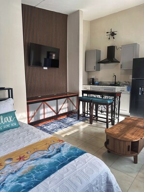 Ein modernes Schlafzimmer mit Bett, Schreibtisch und einer Küchenzeile.