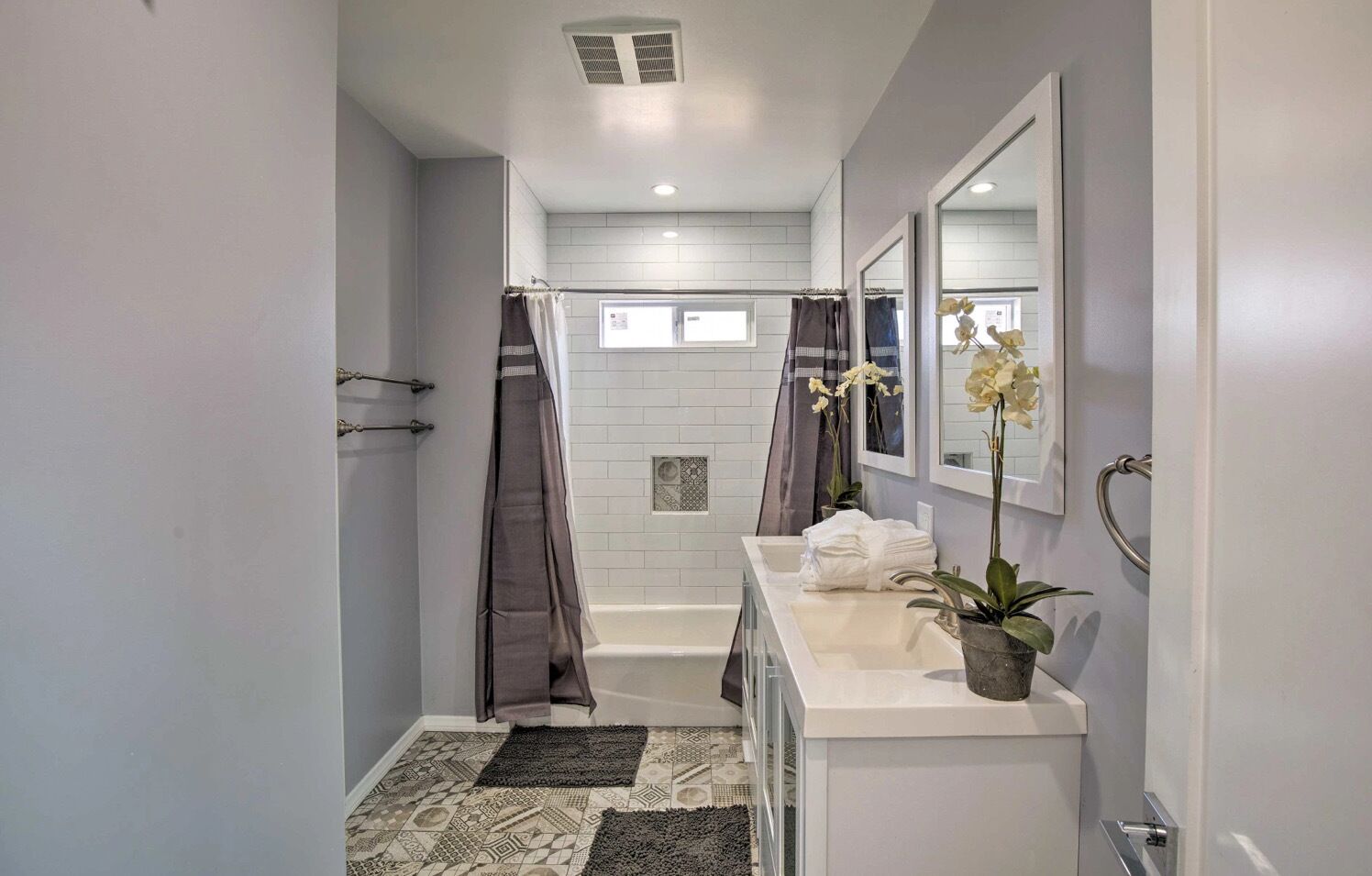 A modern bathroom with a shower, a bathtub, a sink with a mirror, and a potted plant.