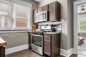 A compact kitchen with a built-in oven, microwave, and a stovetop. - The Cove in St. Louis by StayLage (Saint Louis)