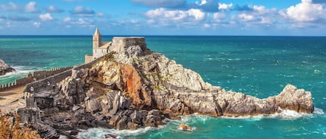 A coastal fortification with a tower, surrounded by rocky terrain and the sea.