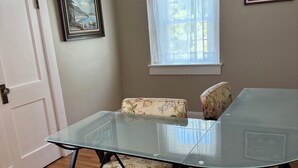 Un comedor con una mesa de vidrio y sillas con estampado floral.