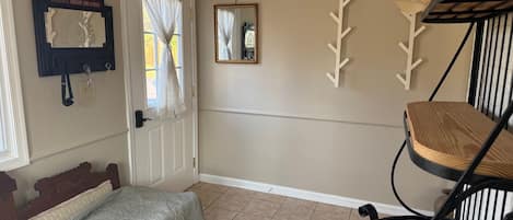 A room with a bed, a chair, a door with a mirror, and wall decorations.